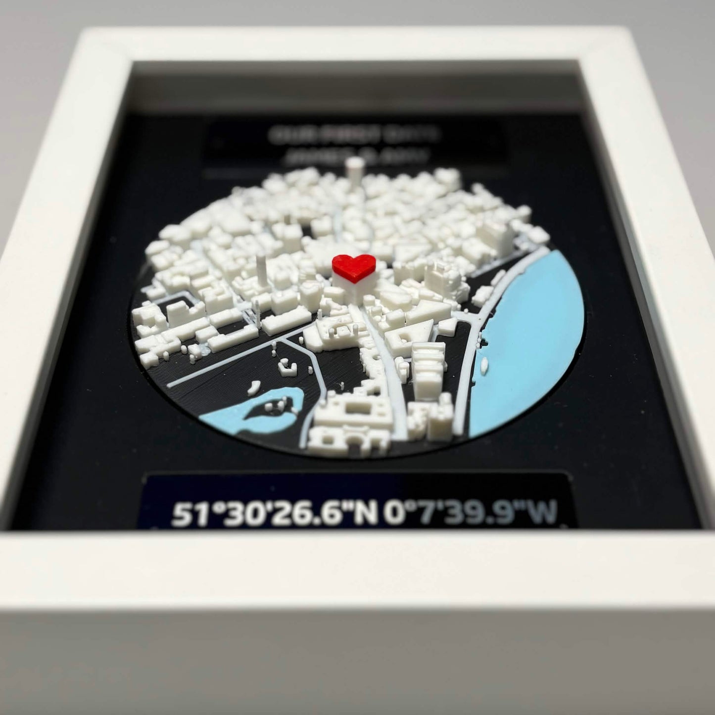 Close-up angled view of 3D printed map model with red heart pin and coordinate plaque.