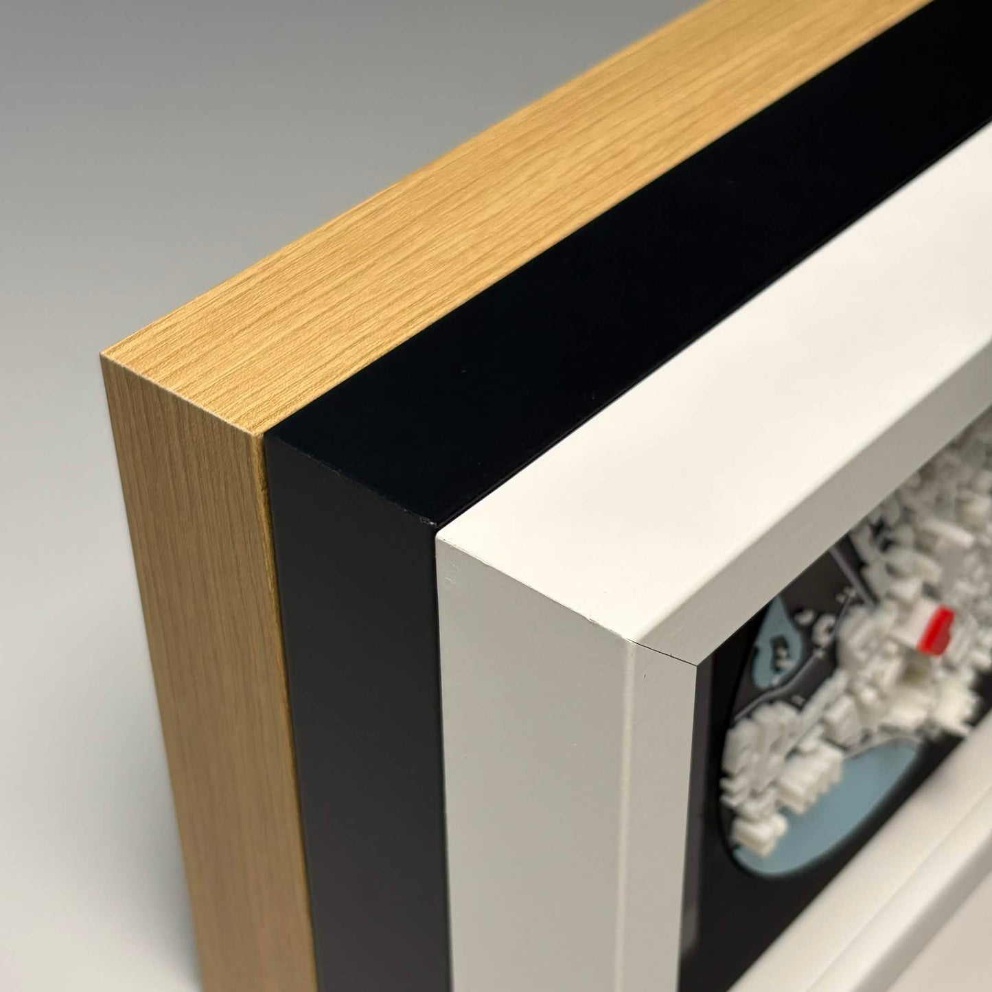 Close-up comparison of oak, black, and white frame edges side by side.