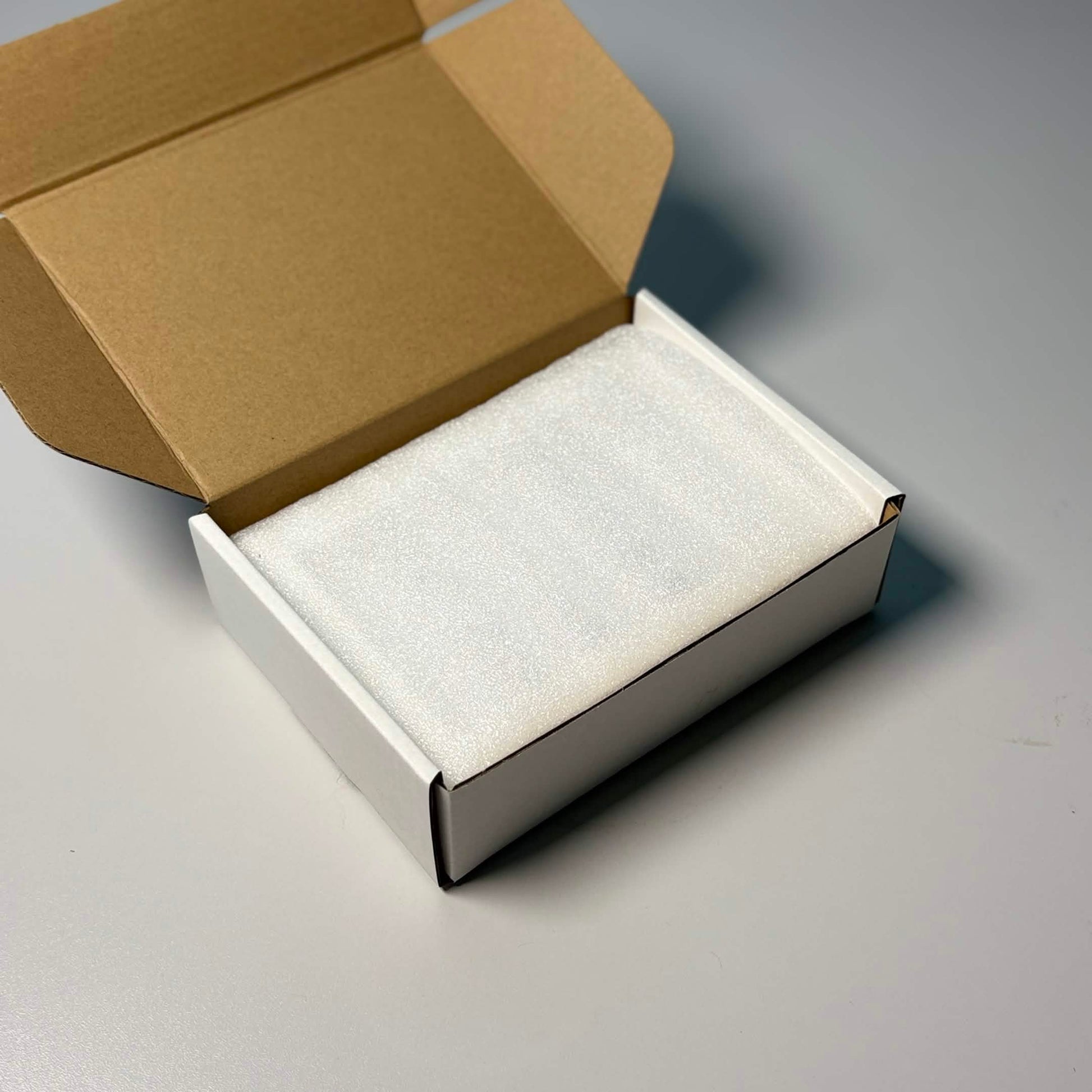 Product packaging showing protective foam wrapping inside white gift box.